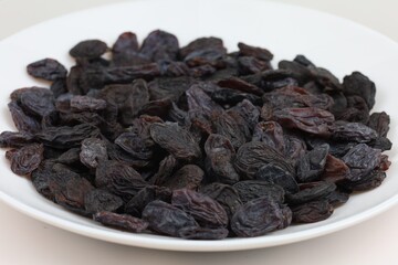 Black raisins arranged neatly on a white plate for display