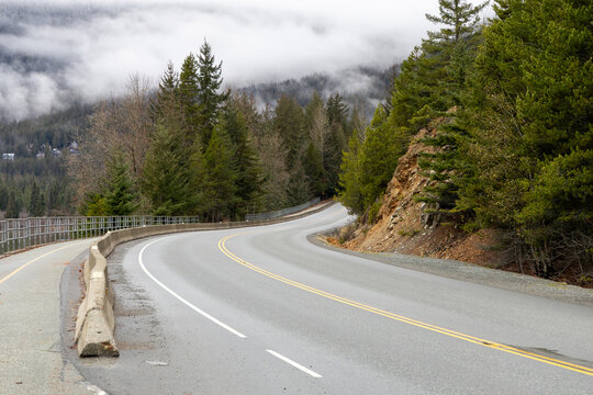 Winding Mountain Road Through Dense Forest With Snow-Capped Peaks Near Whistler, BC, Canada