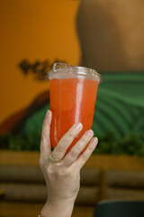 Hand Holding a Cold Red Refreshing Drink in Plastic Cup