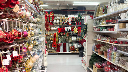 Festive holiday store aisle filled with colorful Christmas ornaments, garlands, ribbons, toys and decorative figurines creating a bright and cheerful seasonal display