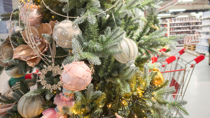 Elegant Christmas tree decorated with pastel ornaments, sparkling beads and warm fairy lights inside a holiday-themed store aisle