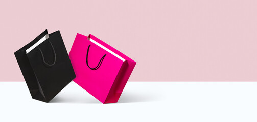 Black and pink paper shopping bags on light pink and white background. Concept of modern fashion retail, holiday sale branding, online shopping delivery promotion and seasonal holiday discounts mockup