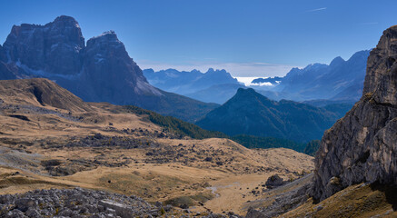 Autumn landscape in Croda da Lago circuit hike in the Ampezzo Dolomites. Large meadow in the foreground, chain of mountain ridges covered by clouds in background. Family vacation in Dolomites, Italy