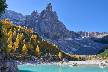 The mount Sorapiss towers directly above Lake Sorapis and forms the dramatic backdrop visible from the lake&rsquo;s shore. The strong turquoise color of the lake. Autumn landscape with golden larch trees.