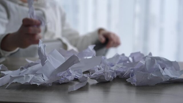 A man is experiencing a fit of anger and aggression at work.
A man tears up papers and scatters them around the office in anger.
A man working in a bright office is experiencing negative emotions.