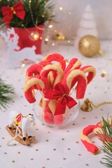 Christmas candy cane shortbread cookies in a clear glass vase with Christmas decor on a light tablecloth. Merry Christmas.