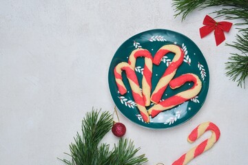 Christmas candy cane shortbread cookies on a green plate with Christmas decor against a white concrete background. Merry Christmas.