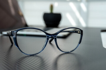 Stylish blue eyeglasses resting on a textured black surface in a well-lit indoor space