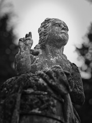 Weathered stone angel statue making a blessing gesture at Goat Gate Cemetery in Bratislava.