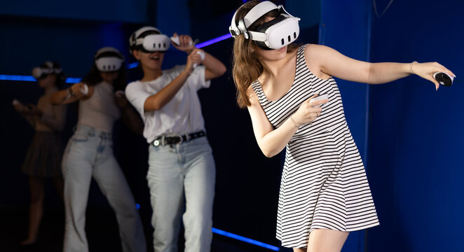 Young girls friends using virtual reality glasses - people having fun with new technology vr headset