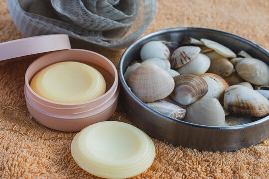 Self care and beauty ritual with solid wellness product, natural bath and body soap, seashells, and shower pouf on soft orange towel for relaxing spa experience
