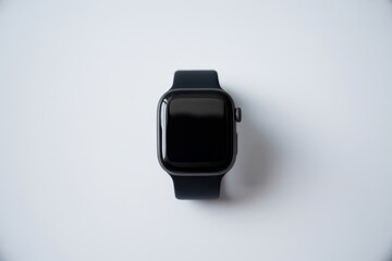 Overhead view of a black modern smartwatch on a clean white surface, showcasing minimalist technology and wearable design