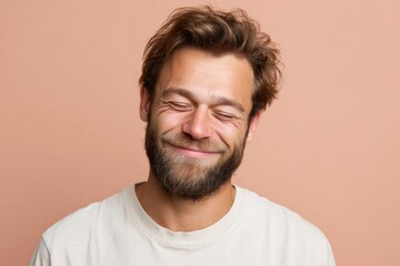 Obraz premium Smiling young man with beard on peach background