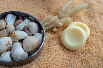 Spa still life with natural round soap bars, seashells and dried pampas grass on a soft orange towel, evoking serene, organic self care and relaxing bathroom ritual