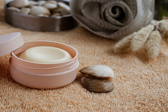 Open container of nourishing moisturizing cream for skincare routine during a relaxing spa and wellness treatment with seashells and soft towels, promoting beauty and self care
