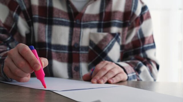 A person opens a pink highlighter and draws lines on a white sheet of paper.
Circle important information on a piece of paper.
Circle text with a marker.