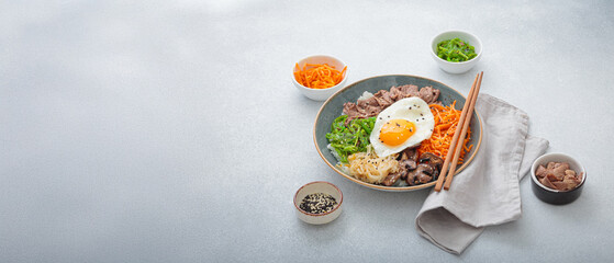 Traditional korean bibimbap with fried egg, beef and vegetables and other toppings on light