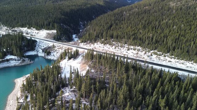 Aerial footage of a turquoise lake surrounded by steep mountain walls and evergreen forest. Dramatic light and winter atmosphere.