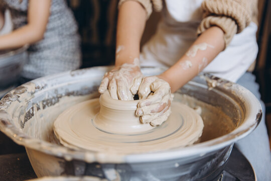 Children learning pottery craft on a potter's wheel