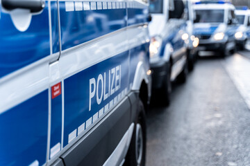 Riot police cars are standing on the side of a political rally or demonstration against the corona...
