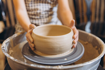 Child hands crafting clay bowl on pottery wheel