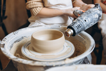 Child learning pottery using potter's wheel and heat gun
