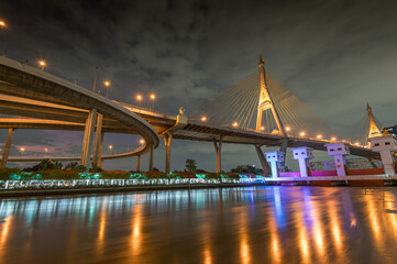Fototapeta premium View of the Bhumibol Bridge, also known as the Industrial Ring Road, during sunset. This iconic structure connects Bangkok and Samut Prakan by spanning the Chao Phraya River twice.