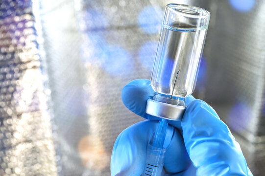 Medical personnel filling a syringe needle with generic vaccine booster from vial