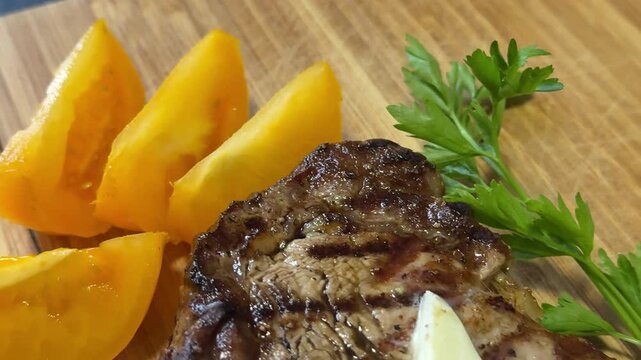 yellow tomato slices and entrecote beef steaksauce to traditional ossobuco dish at wooden table, closeup
