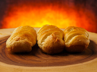 Premium golden French brioche rolls on a wooden board with red hot burning style background. Fine and delicate dessert. Top quality pastry product.