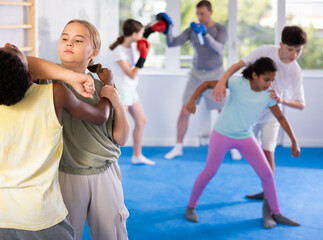 Obraz premium Girls and boys learns to do power grip with trainer during a self-defense lesson in the gym