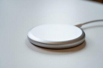 Silver and white wireless charging pad glowing slightly on a bright surface, symbolizing connectivity, smart power transfer, and futuristic tech concepts.