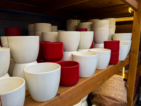 Different empty ceramic flower pots on wooden shelf at a gardening shop