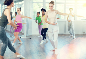Group of boys and girls teenage dancers performing ballet movements in dance class