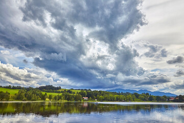 Blick auf den Bayersoiener See und dunkle Unwetterwolken, mit Angler, in Bayern, Deutschland.