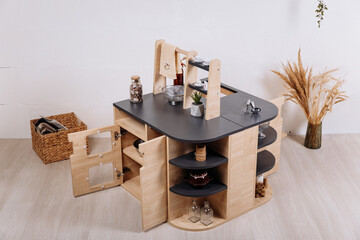 Wooden kids play kitchen island with shelves in minimalist nursery interior