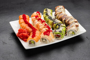 Assorted sushi rolls with salmon, shrimp and avocado on plate, restaurant menu closeup