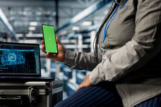 Close up of AI data center admin using green screen smartphone to check messages while taking break. Server hub IT specialist scrolling through social media during downtime at work using mockup phone