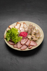 Assorted cold cuts platter with sausages, smoked pork and sauce on ceramic plate
