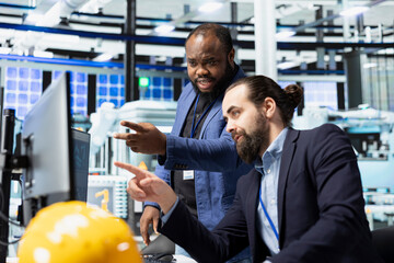 Industrial experts business partners work as a team to refine manufacturing process, ensuring...