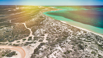 Drone aerial shot of Coral Bay coastline showing clear blue waters and sandy beach in WA
