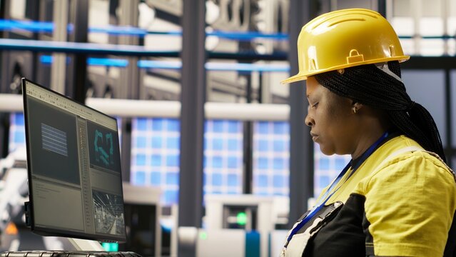 Technician in industrial plant monitors production equipment using PC software, diagnosing malfunctions. Factory employee coordinates repair tasks on assembly lines using computer program, camera B