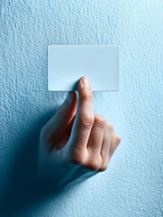 Hand reaching from paper wall offering a blank card