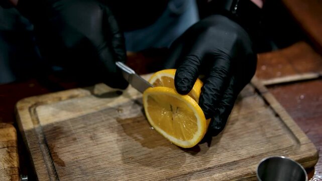 man cutting orange slices on a wooden table in a bright minimalist kitchen. She prepares fresh fruit for a healthy homemade smoothie. . High quality 4k footage