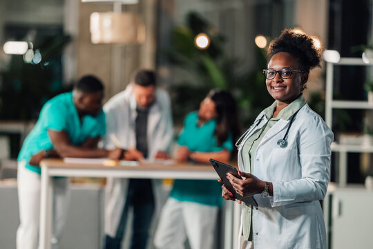Smiling female doctor holding tablet in hospital setting - Powered by Adobe