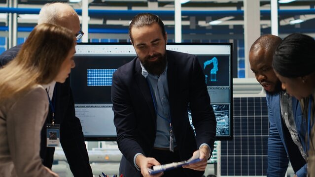 Industrial plant shareholders in meeting looking at compliance records. Investors reading solar panels manufacturing factory paperwork, reviewing financial statements before signing deal - Powered by Adobe