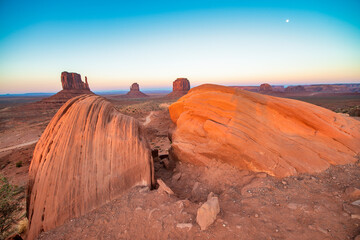 Vast desert landscape of Monument Valley bathed in warm sunlight with dramatic sandstone mesas