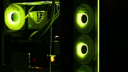 Close-up view of a custom gaming PC interior featuring spinning fans with RGB LED lighting cycling from bright green to blue hues in a dark setting