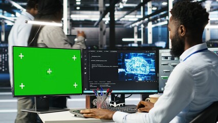 Data center admin using green screen PC to do node tree programming, optimizing resource allocation. Man in server room uses mockup computer predictive AI visualization systems, camera B