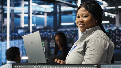 Portrait of joyous server hub technician using AI visualization insights to optimize system health. Joyful data center IT expert analyzing gear issues using node tree tools, camera B